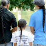 Three people with long braids walking.