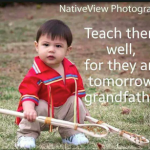 Young boy holding a stick, Native American clothing.